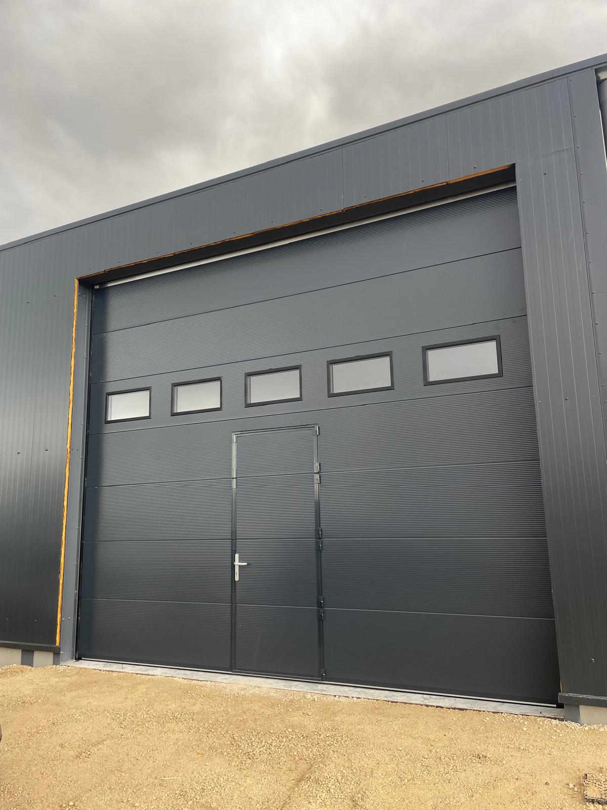 Porte sectionnelle grise avec porte intégrée pour usage professionnel dans le Val-d'Oise (95)